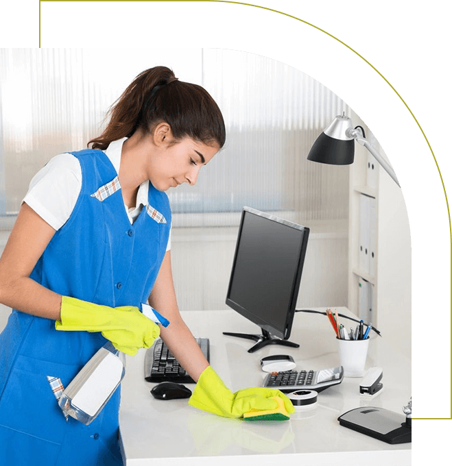 A woman in blue shirt and yellow gloves cleaning desk.
